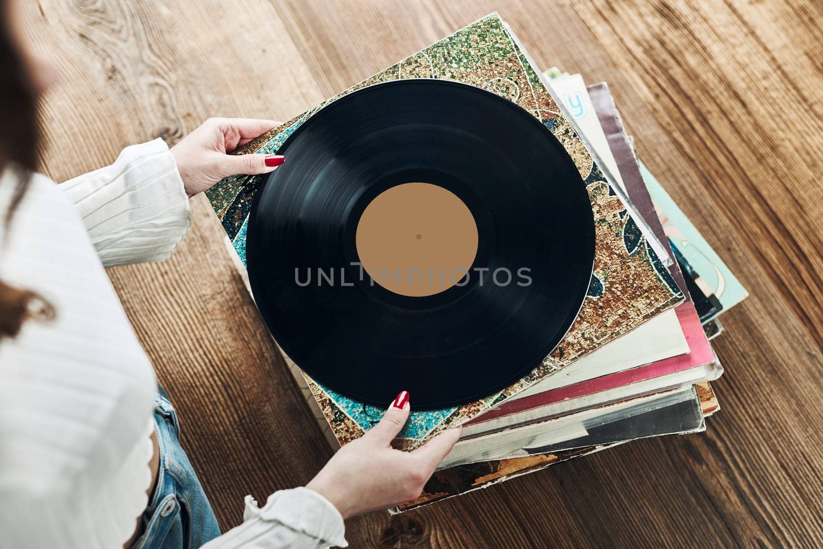 Playing vinyl records. Listening to music from vinyl record player. Retro and vintage music style. Woman holding analog LP record album. Stack of old records. Music collection. Music passion