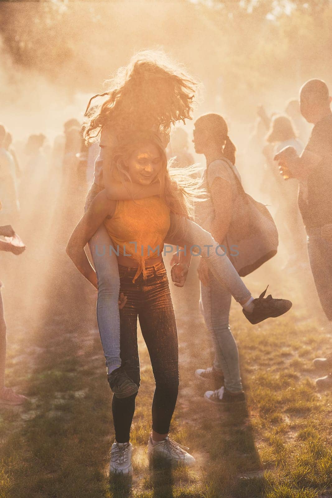 Portrait of happy smiling young girls with colorful paints on faces and clothes. Two friends spending time on holi color festival