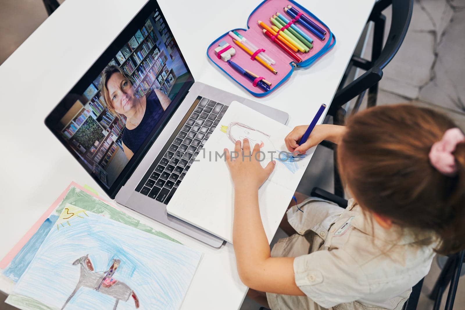 Student litttle girl having video class remotely with her teacher on laptop sitting at desk in after school club at primary school. Back to school. Child using technology on elementary computer science lesson. Smart little girl learning online. Teacher teaching remotely. E-learning classes