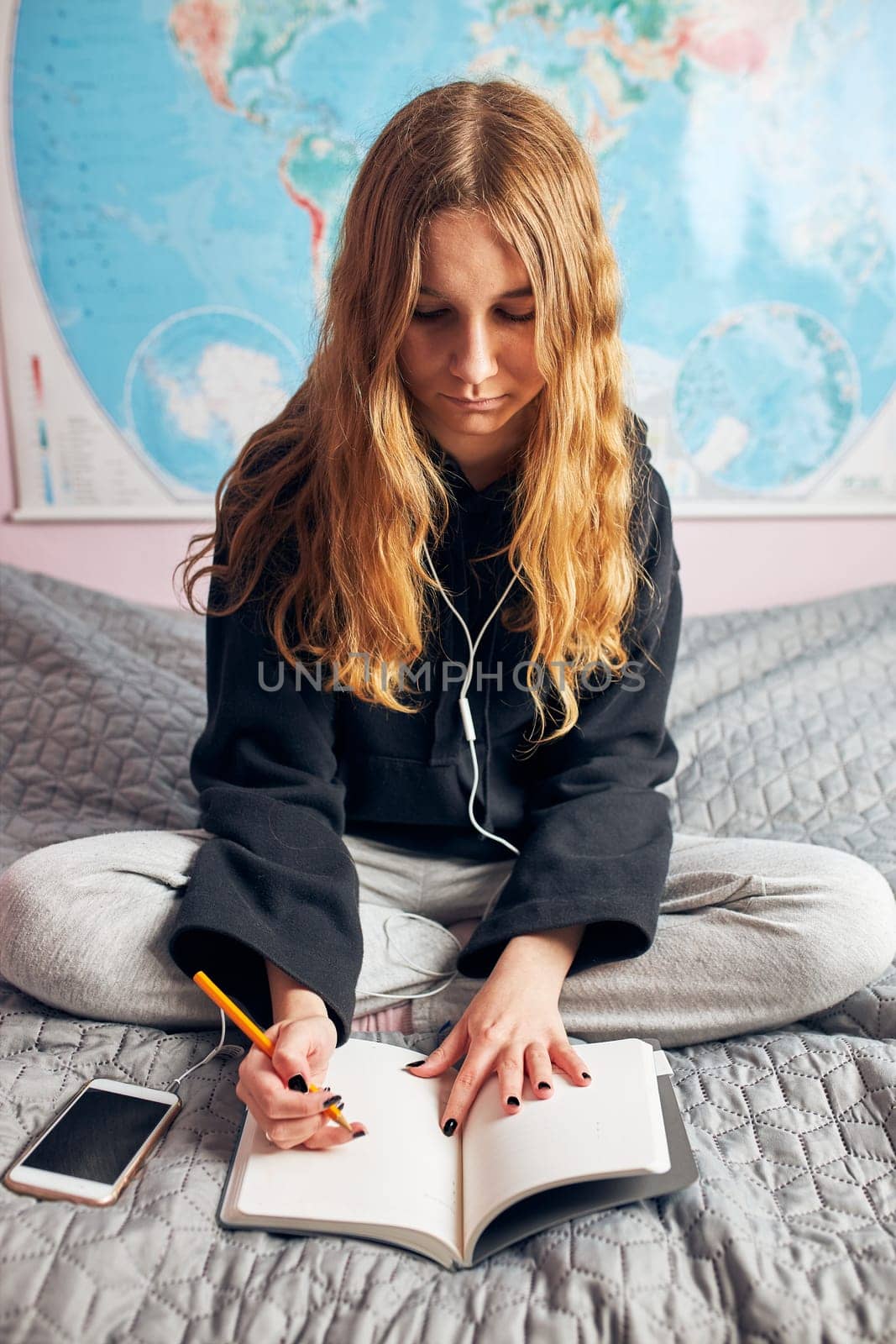 Student learning at home. Young woman making notes, reading and learning from notepad sitting in bed at home during quarantine