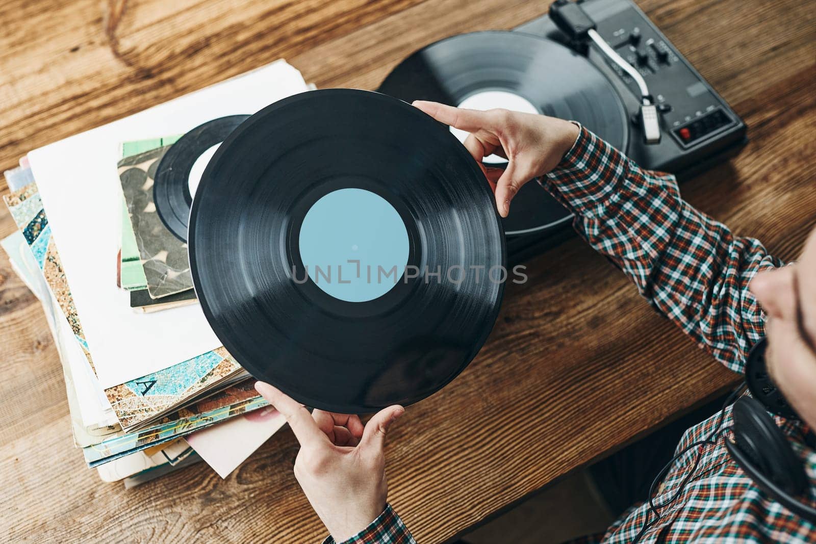 Man listening to music from vinyl record. Playing music from analog disk on turntable player. Enjoying music from old collection. Relaxing at home. Retro and vintage. Music passion