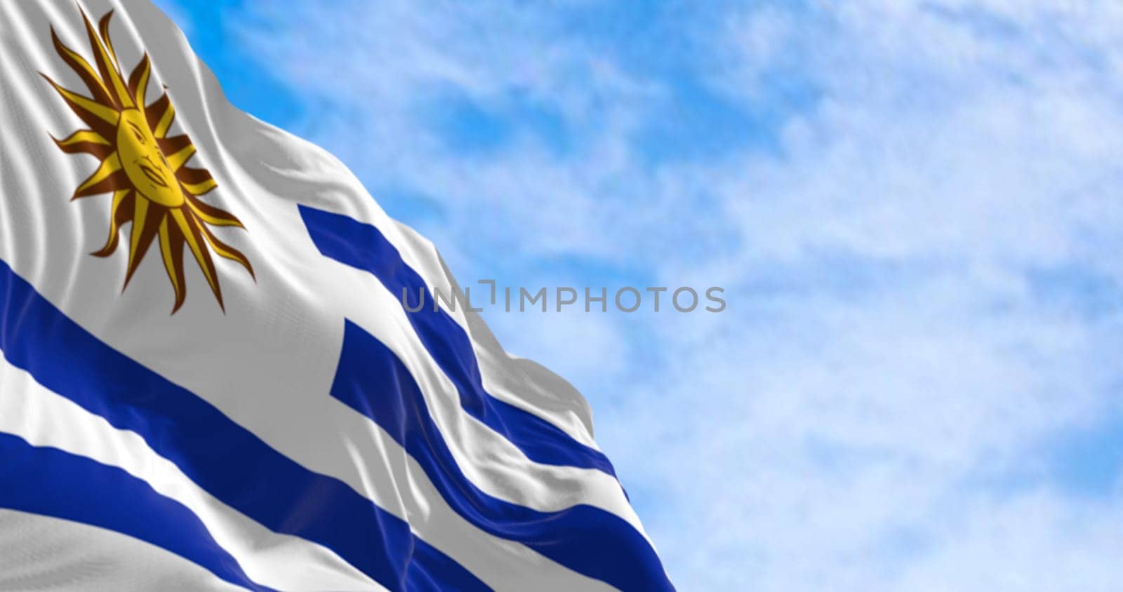 Uruguay national flag fluttering in the wind on a sunny day. 9 horizontal stripes: white and blue alternated, with Sol de Mayo in white square. 3d illustration render.