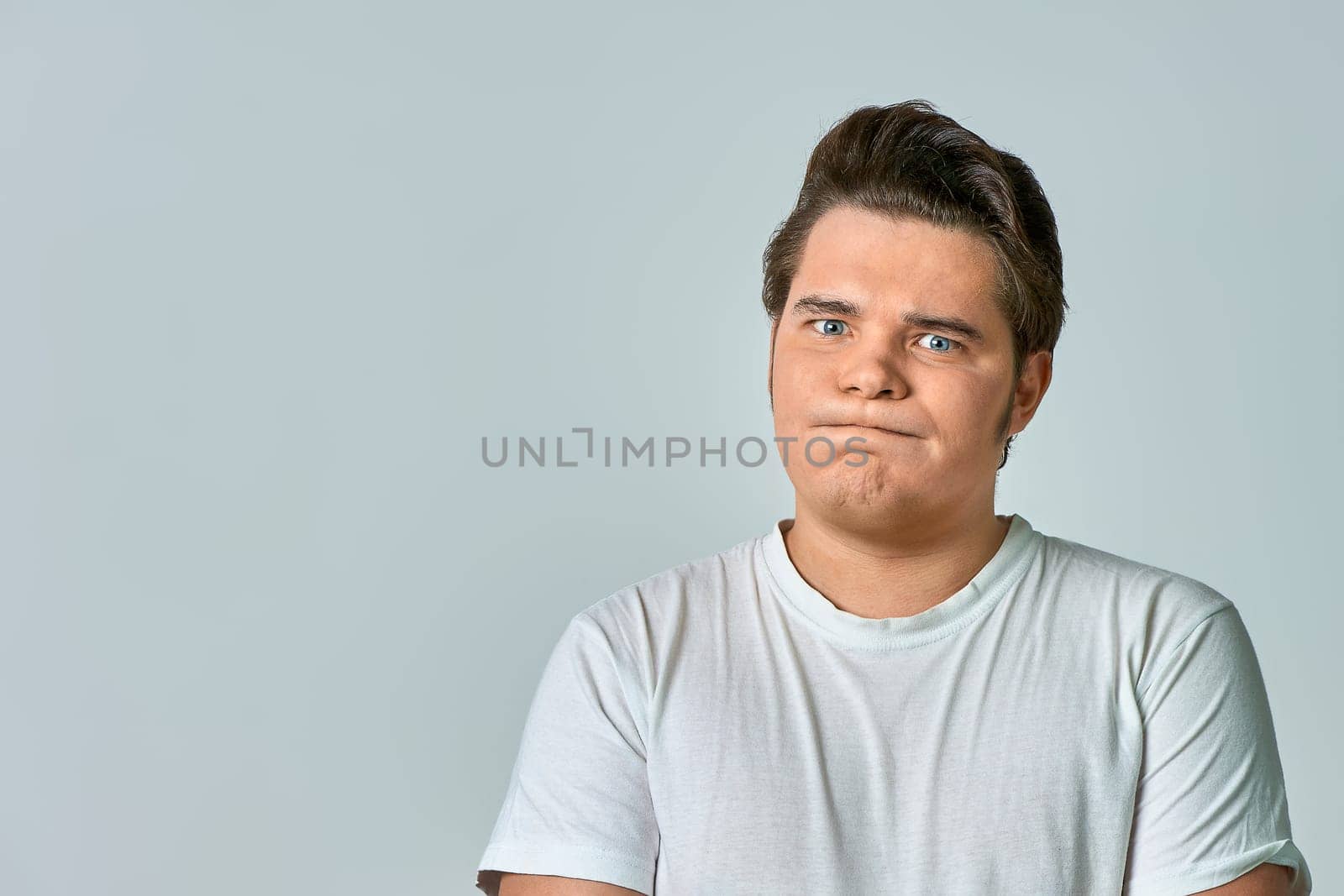 a frowning man on a gray background, copy space. High quality photo