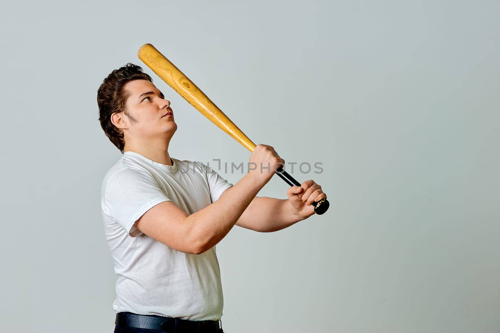 A man with a bat in his hands swings on a gray background. High quality photo