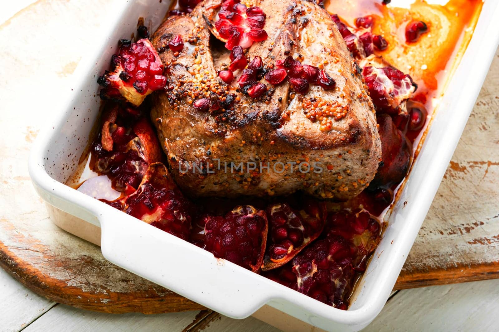 Piece of whole meat roasted with pomegranate seeds for Christmas in baking tray.