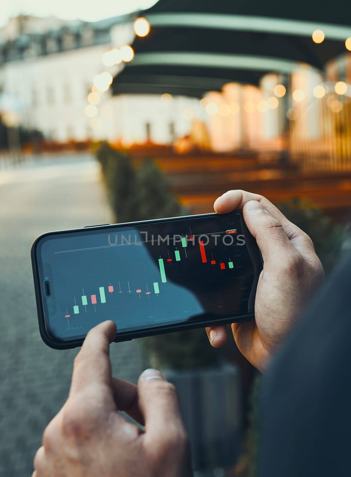 Person investing trading on stock cryptocurrency market using investing application on smartphone. Stock market investment in hand. Trader holding mobile phone looking at candle chart