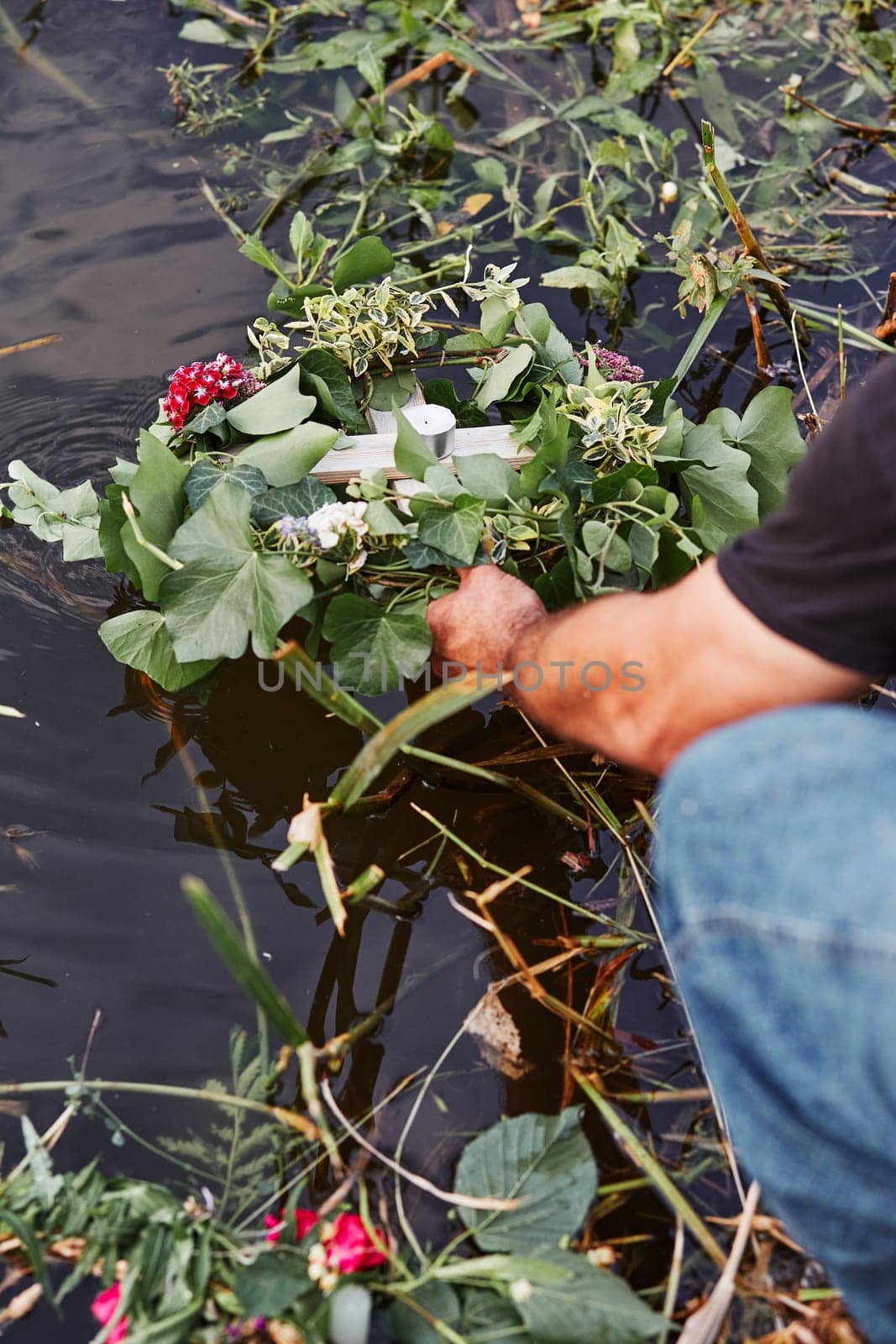 Wreaths of flowers and herbs. Man taking a wreath from a river. Midsummer divination
