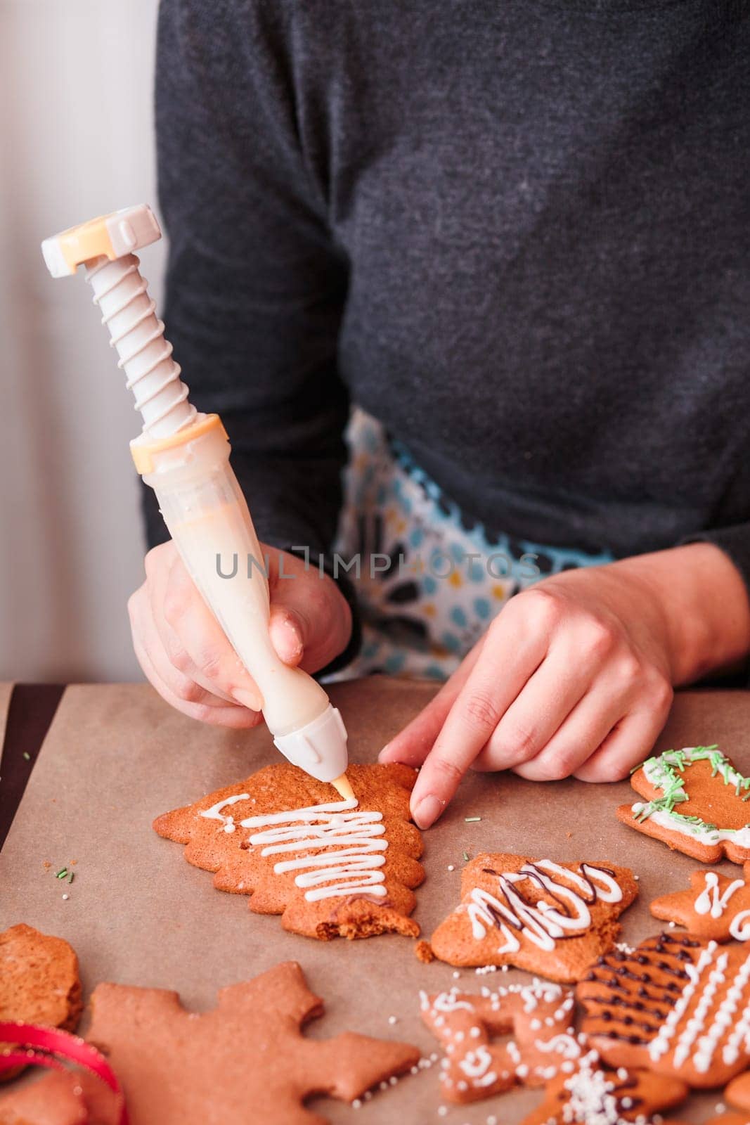 Woman decorating baked Christmas gingerbread with frosting