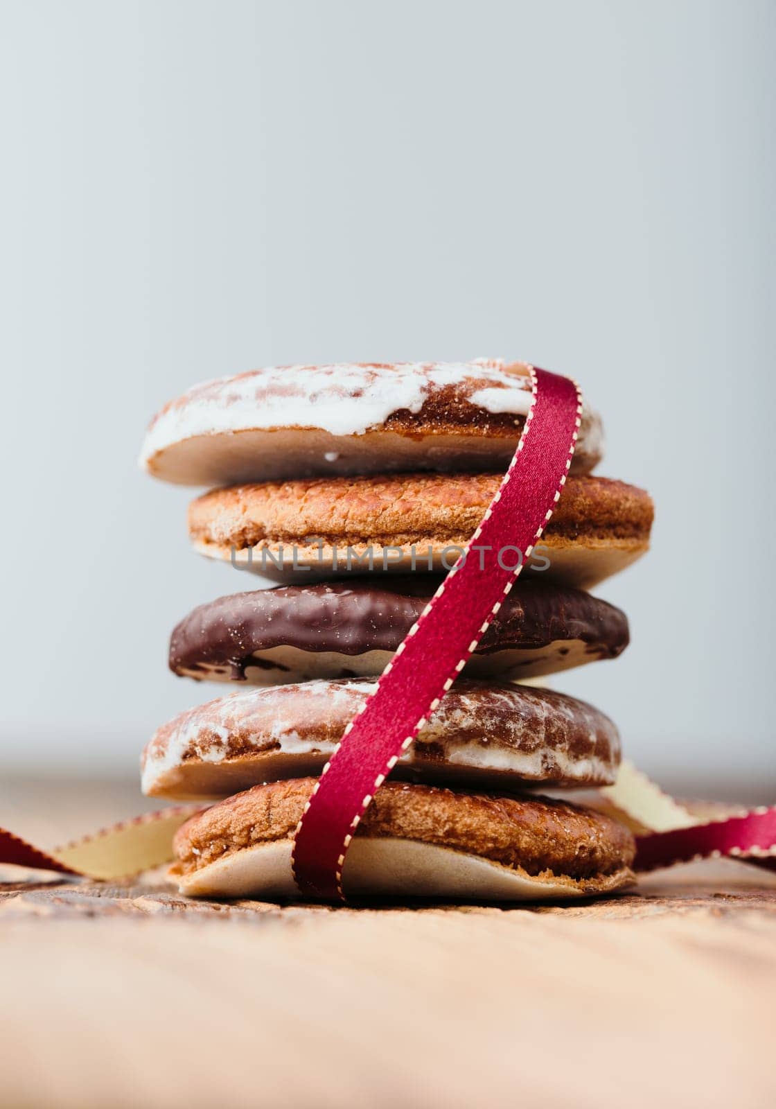 A few gingerbread cookies wrapped in red ribbon Happy Christmas on wooden table. Plain background. Portrait orientation
