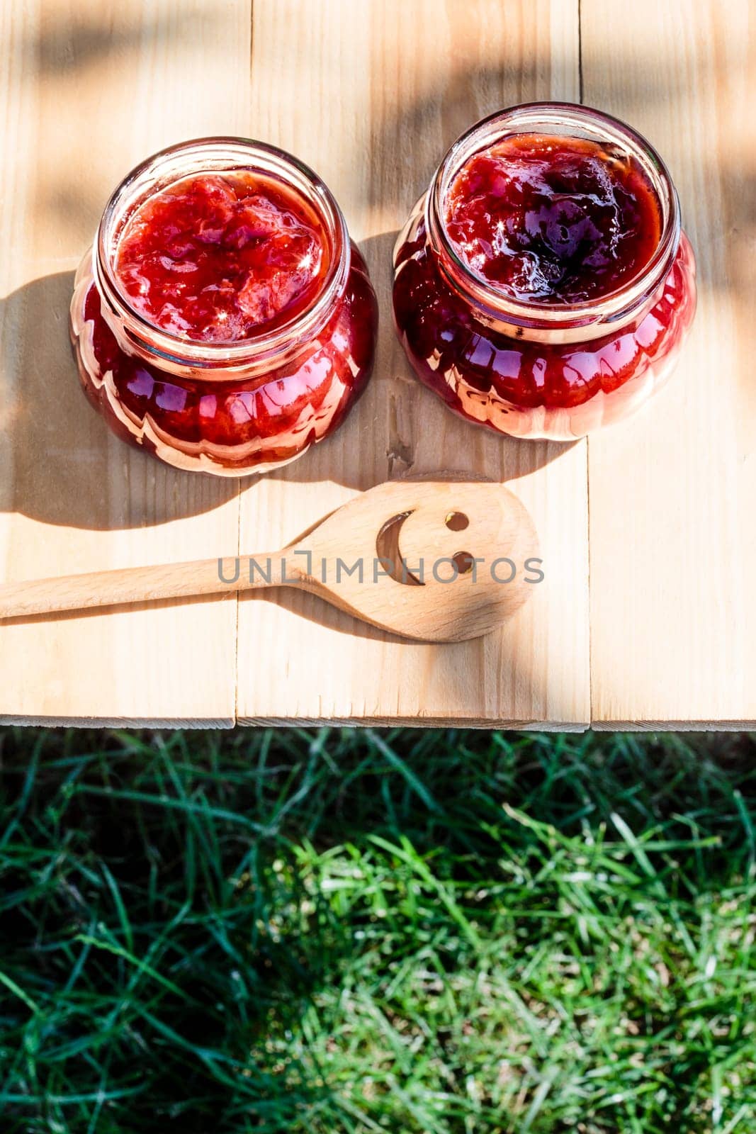 Homemade strawberry jam in jars on wooden table in the garden
