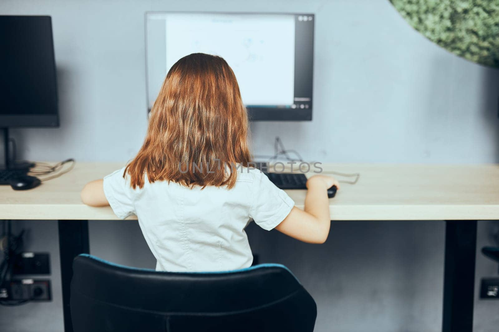 Child learning to use technology in classroom at primary school. Schoolgirl using computer on elementary computer science class. Smart little girl learning programming and coding at school. Engaged child solving riddles on personal computer. Back to school