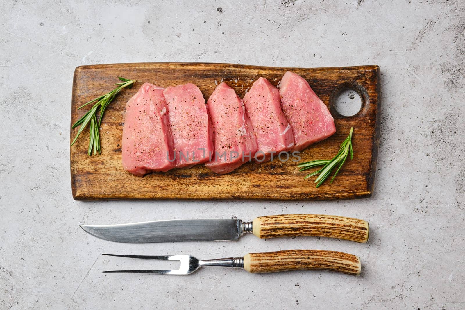 Top view of pork steaks sliced into portions on wooden cutting board