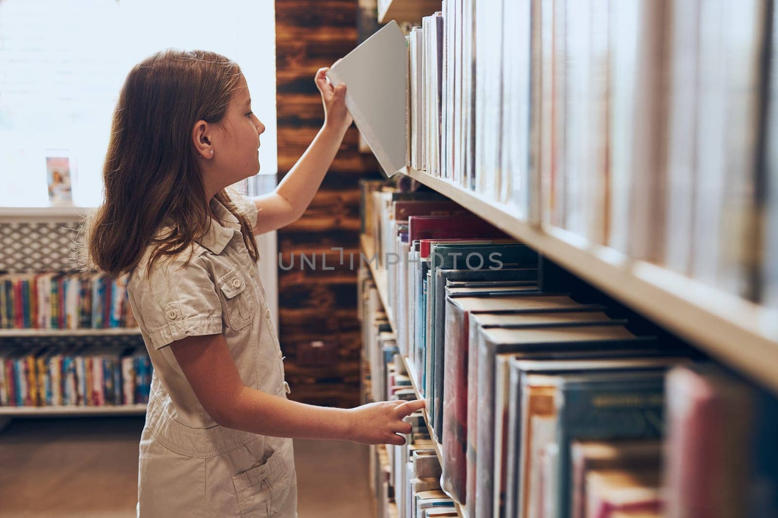 Schoolgirl choosing book in school library. Smart girl selecting books. Books on shelves in bookstore. Learning from books. School education. Benefits of everyday reading. Child curiosity. Back to school