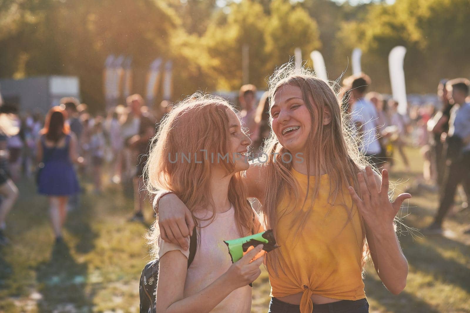 Portrait of happy smiling young girls with colorful paints on faces and clothes. Two friends spending time on holi color festival