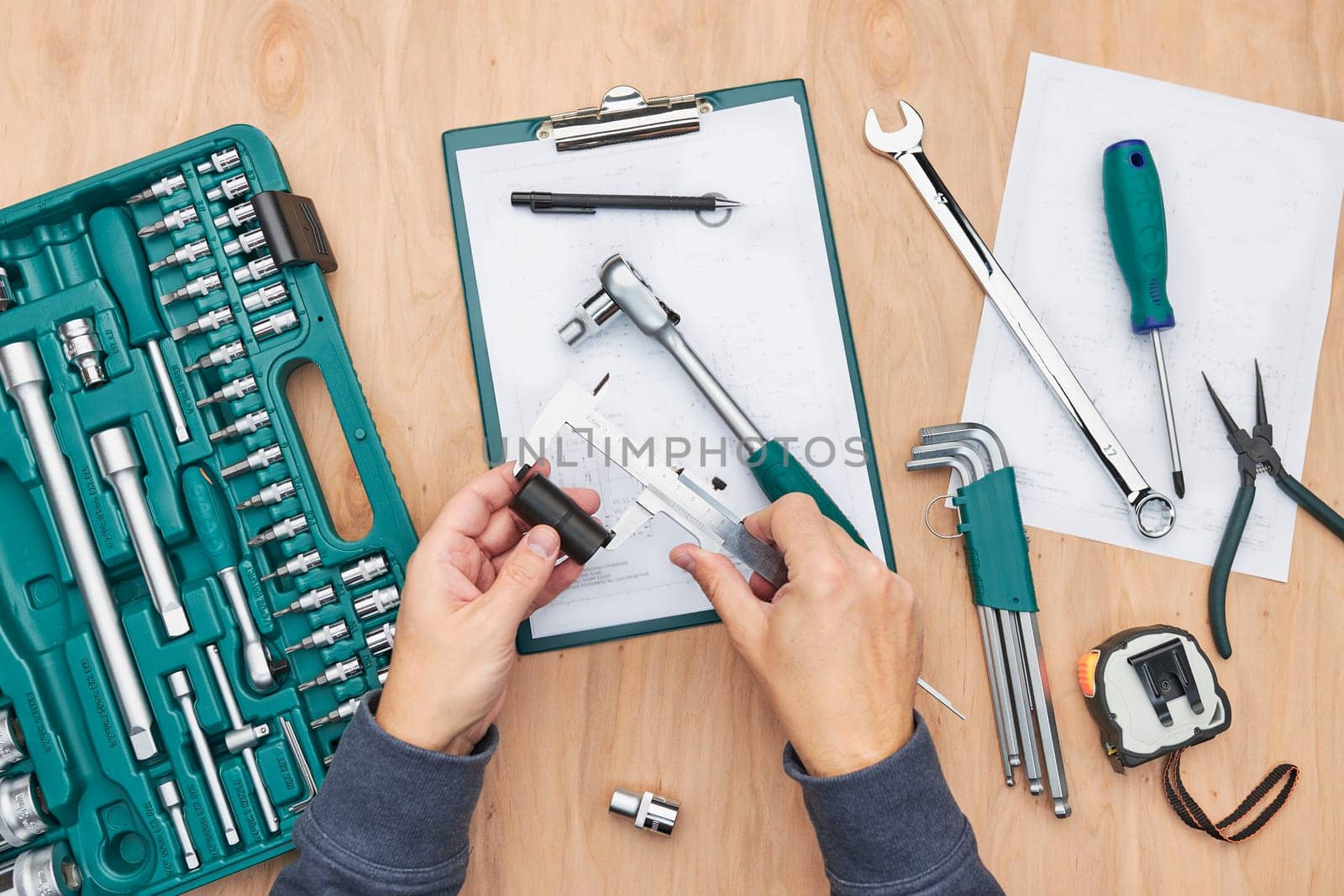 Man working in workshop using many tools. Wrench, spanner, calliper and ratchet with many attachments. Work tools. Universal tool set. Professional equipment