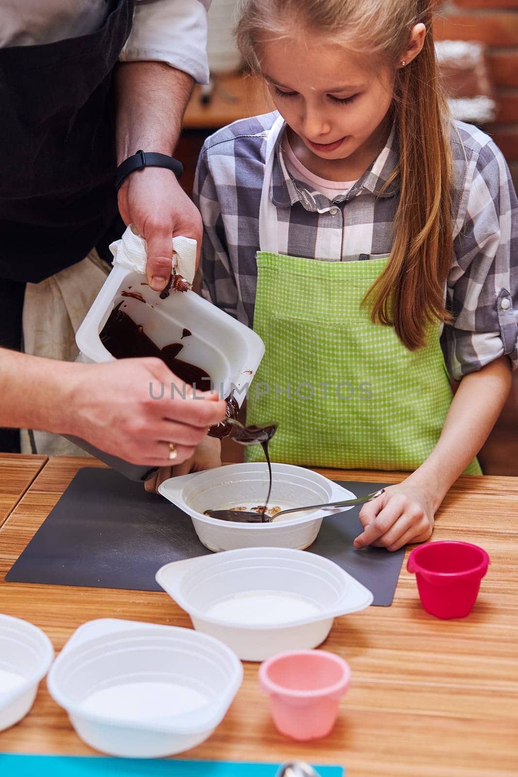 Chef adding hot melted chocolate with cocoa to container. Kid taking part in baking workshop. Baking classes for children,  aspiring little chefs. Learning to cook. Combining and stirring prepared ingredients. Real people, authentic situations
