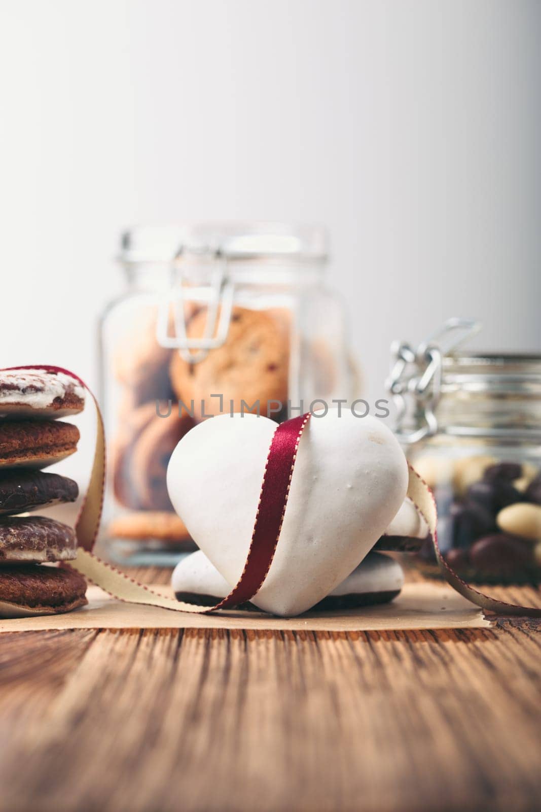 Gingerbread cookies, candies, cakes, sweets in jars on wooden table. Portrait orientation