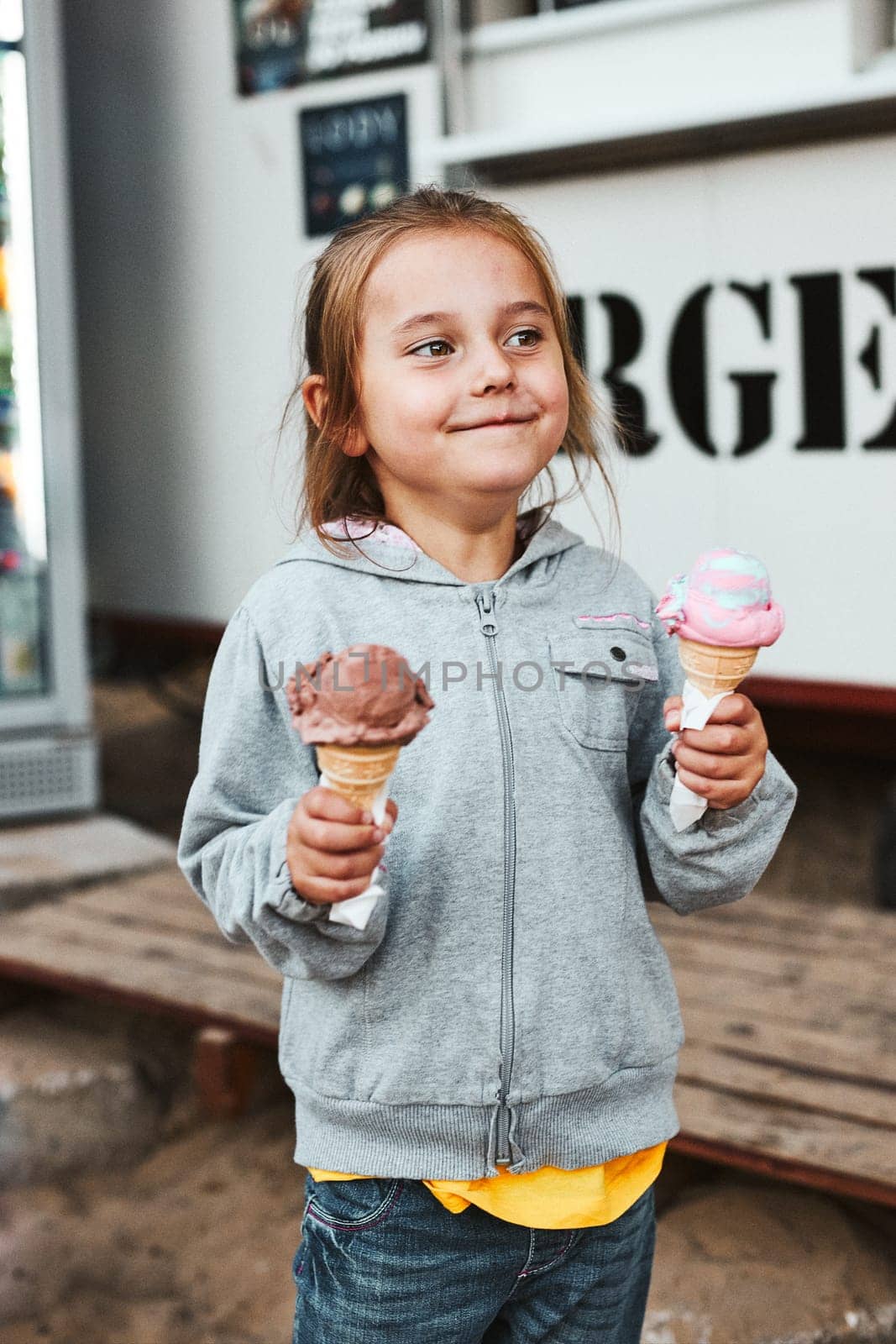 Happy smiling little girl holding two ice cream standing in front of food truck spending time on summer vacations