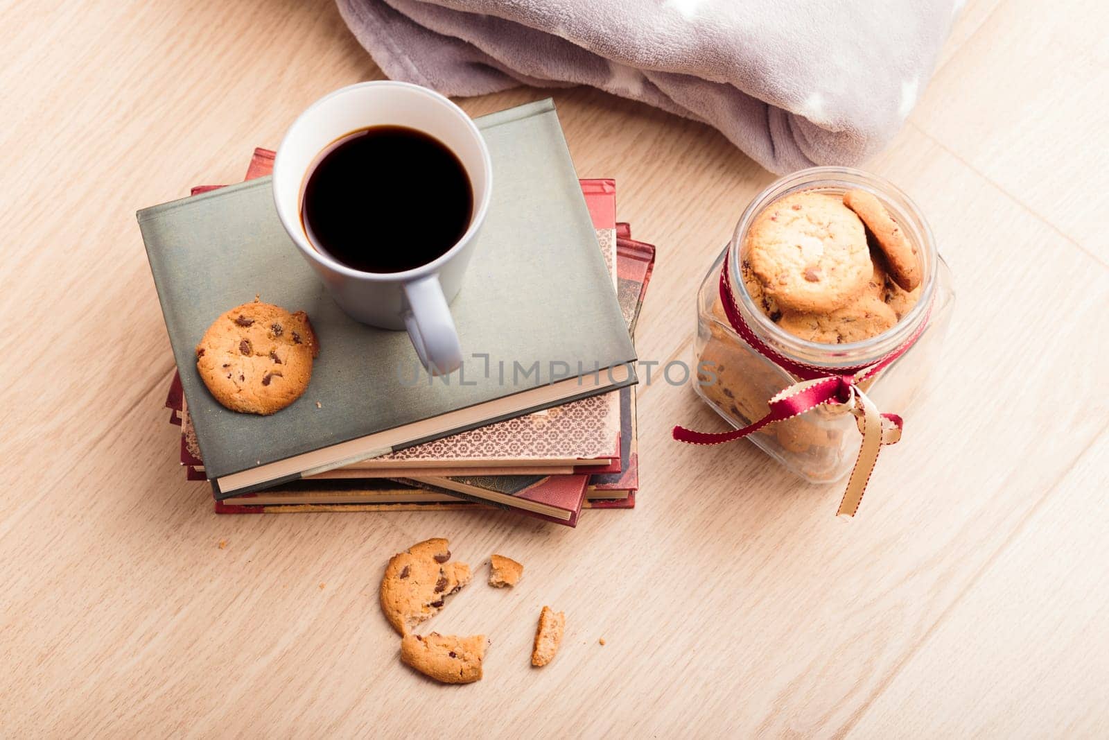 A few books with cup of coffee and cookies on wooden floor