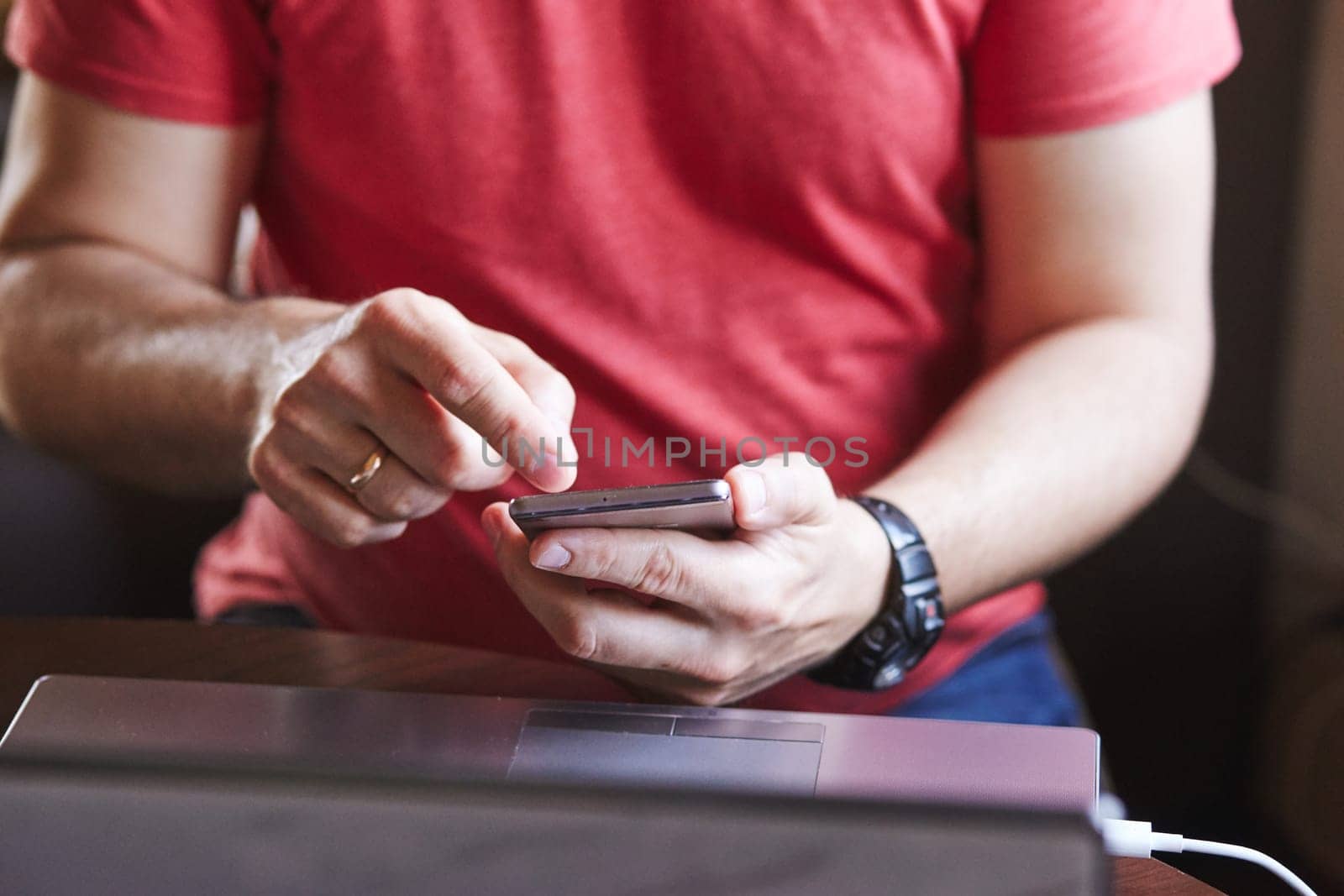 Man using smartphone working on laptop sitting at a desk
