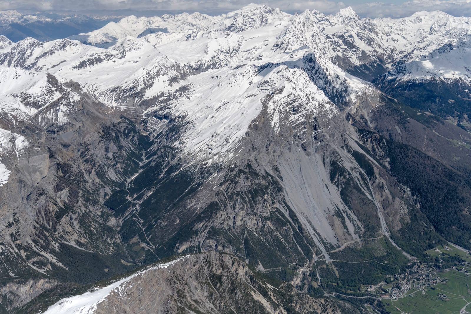 aerial landscape, from a glider plane, of Stelvio pass road  among rocky snowy slopes, shot from west in bright late spring light, Sondrio, Italy