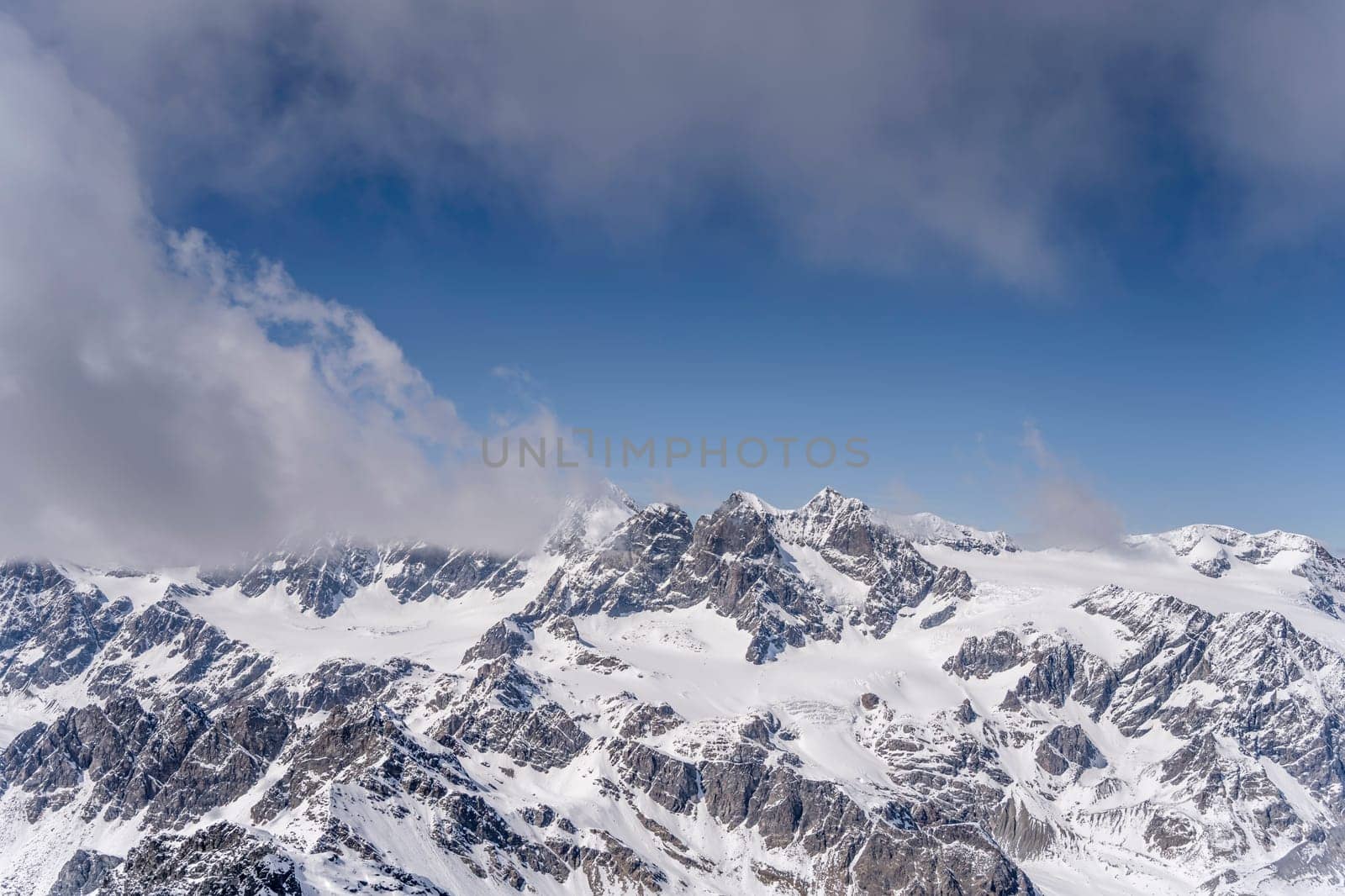 aerial landscape, from a glider plane, of Bernina summit looming out of clouds, shot from south in bright late spring light, Sondrio, Italy