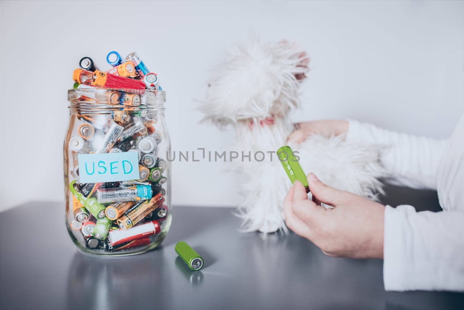 Little girl removing used batteries from toy and putting into jar for recycling. Child separating waste. Batteries only container. Jar filled with discharged used batteries. Waste disposal and recycling. Separating the waste. Batteries only container