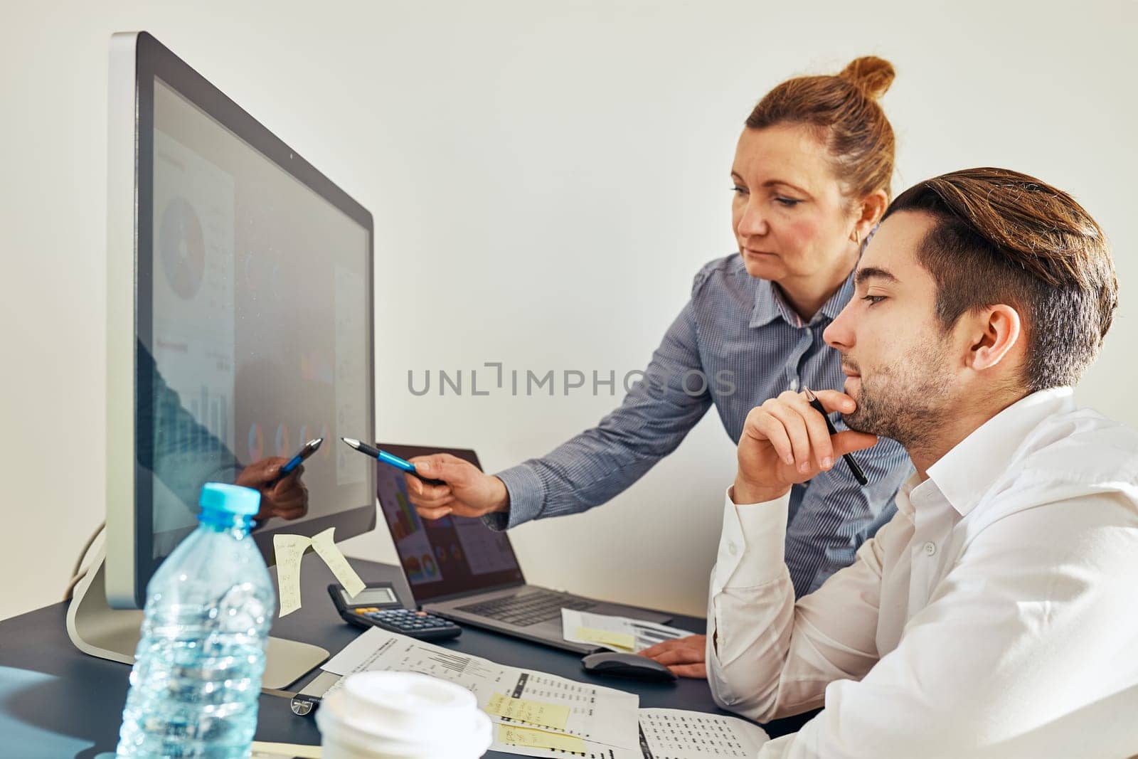 Business colleagues discussing financial data working together in office. People entrepreneurs working with charts and tables on computer. Two people working together. Workmates talking about project