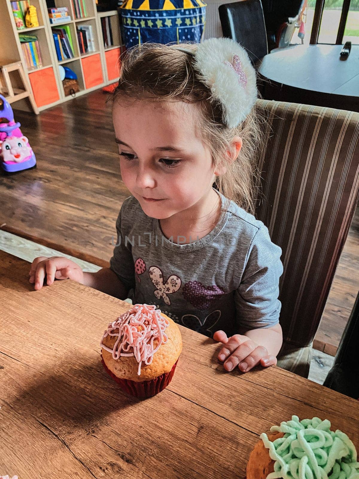 Group of children baking cupcakes, squeezing cream from confectionery bag, preparing ingredients, topping, sprinkles for decorating cookies. Kids cooking, working together in kitchen at home. Concept of happy family