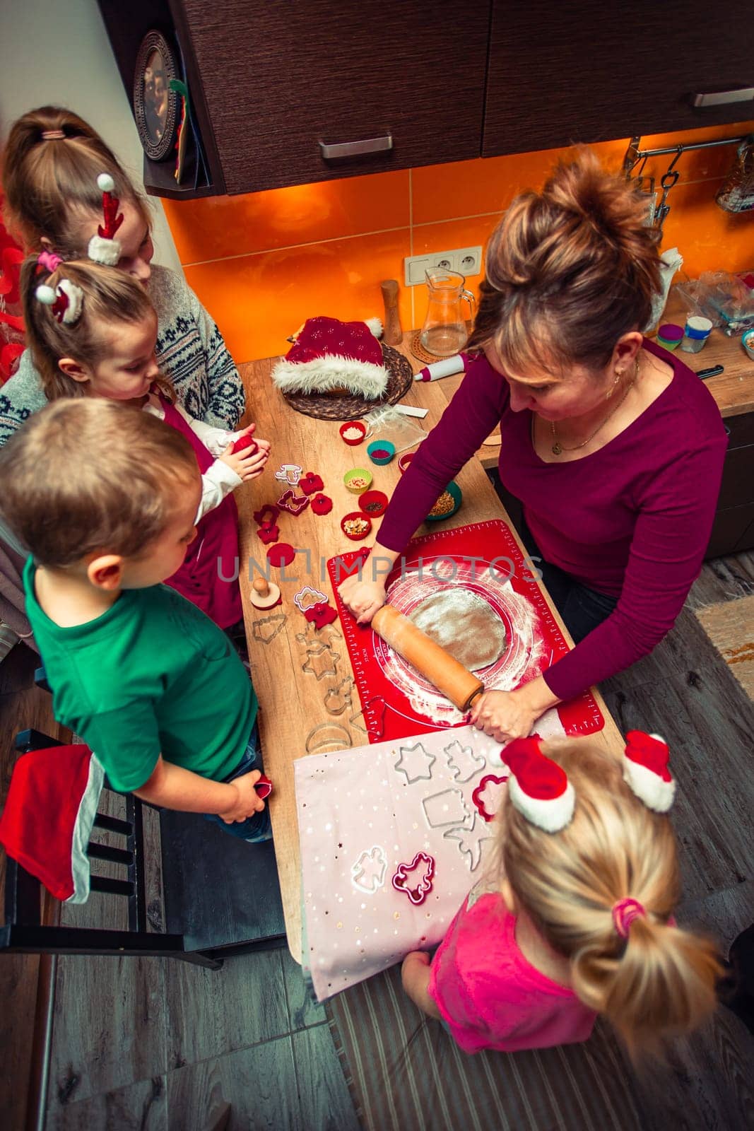 Baking Christmas cookies. Christmas gingerbread cookies in many shapes decorated with colorful frosting, sprinkle, icing, chocolate coating, toppers, put on table. Baking traditional cookies. Family celebrating Christmas. Baking at home. Baked sweet cookies. Coating with frostings. Colouring cookies. Decorating baked cookies. Decoration and design of food. Flat top-down composition. Sweet dessert food. Putting a frost, frosting gingerbread. Shot from above
