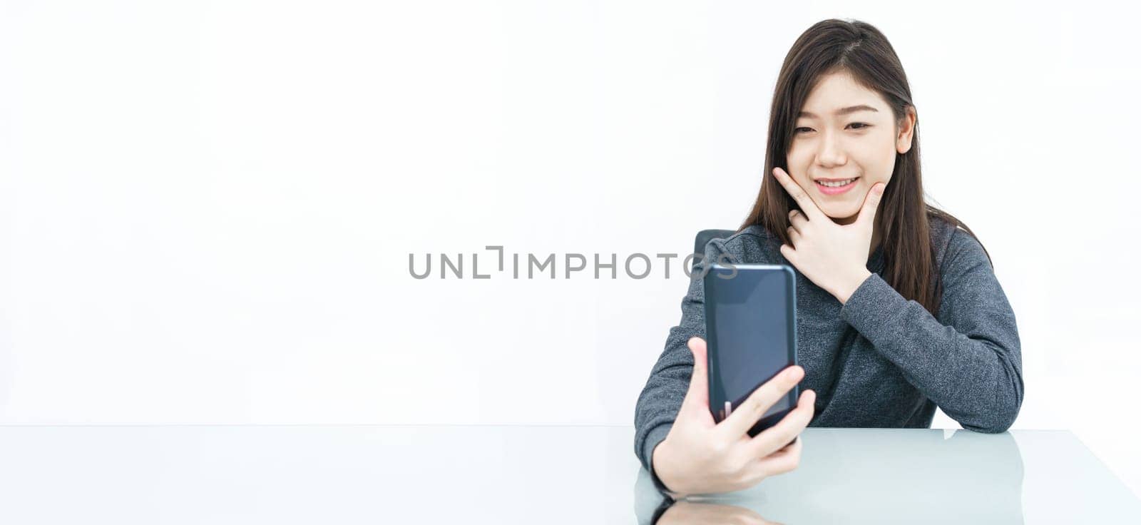 Close up woman long hair writing notebook and using mobile phone on white background