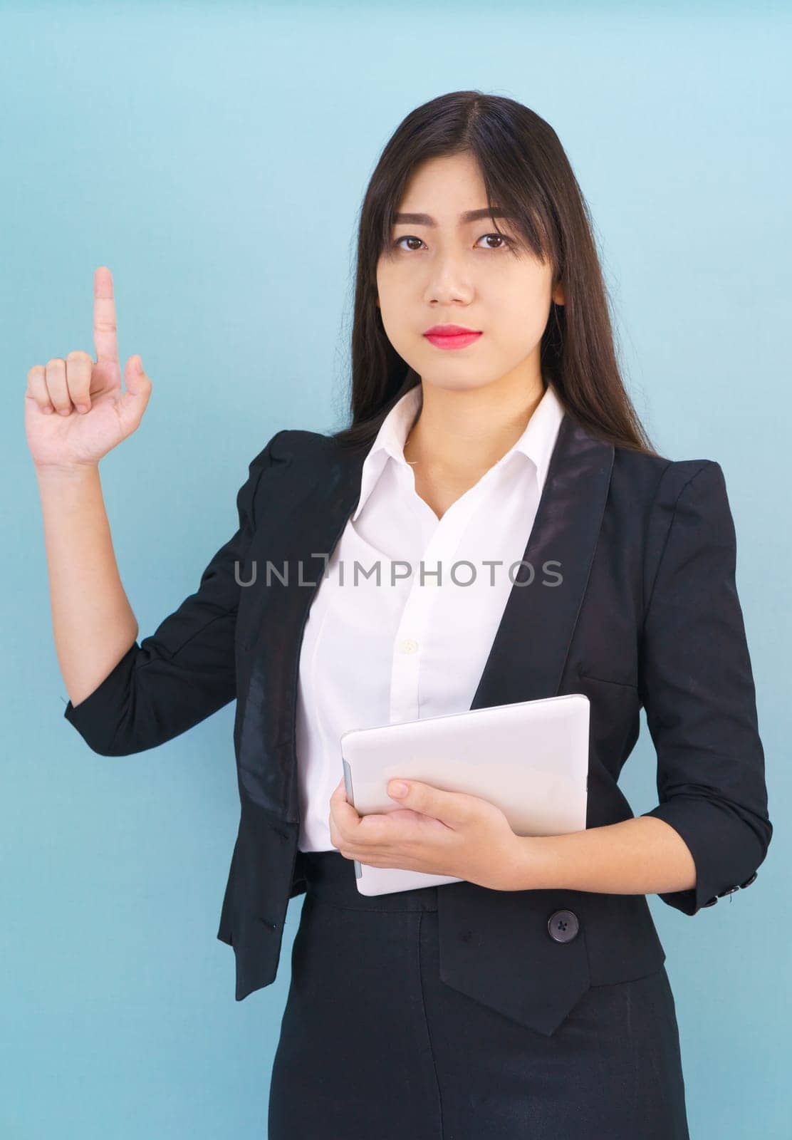 Young women standing in suit holding her digital tablet computor against blue background