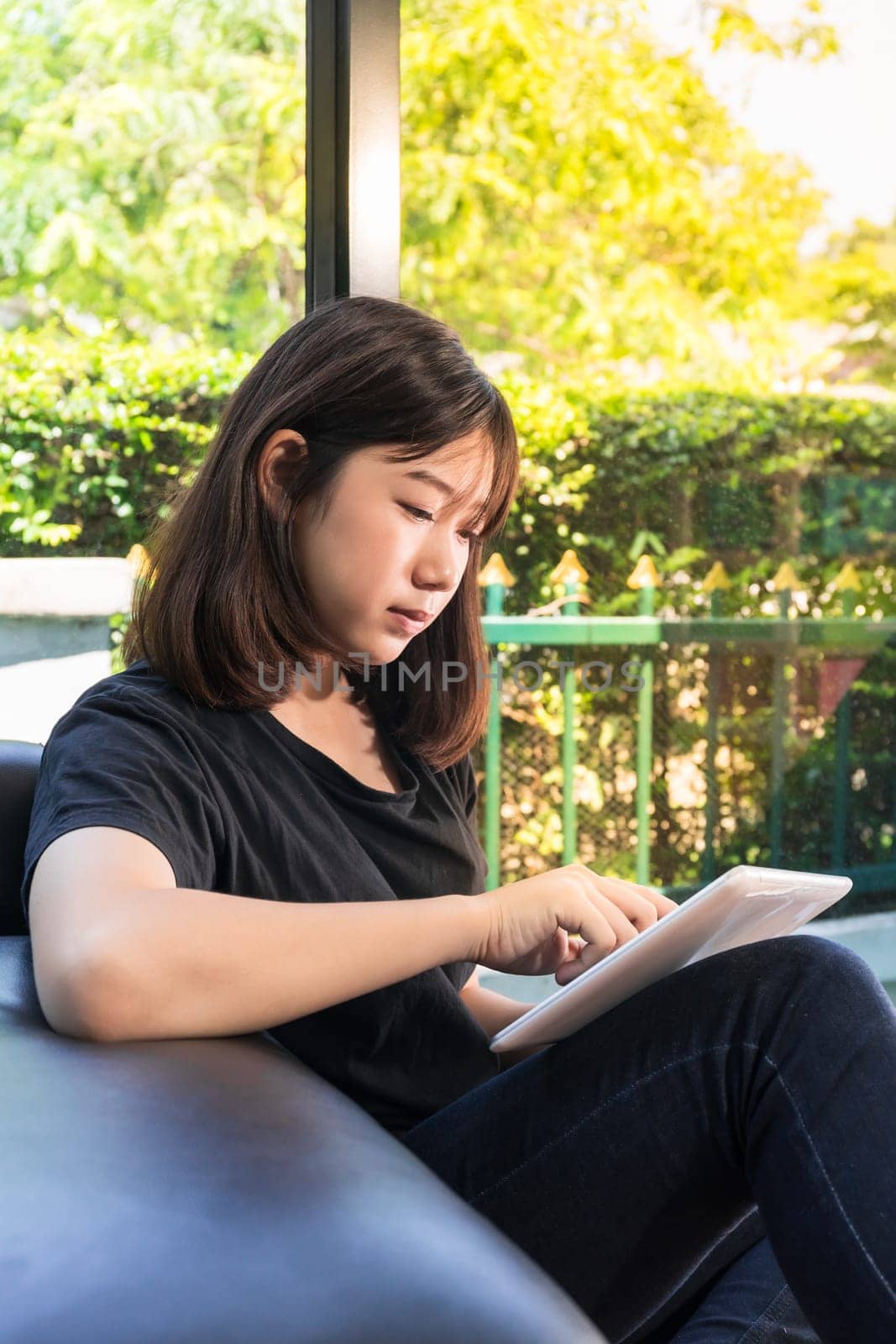 Young girl studying online from digital tablet on the sofai n living room at home