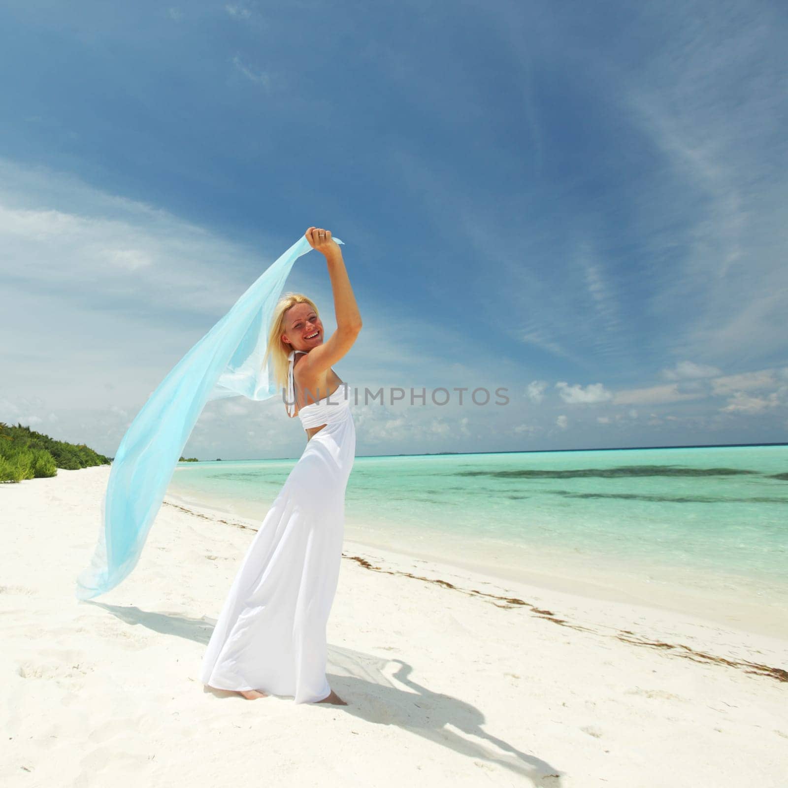 woman with a white fabric in his hands on the beach