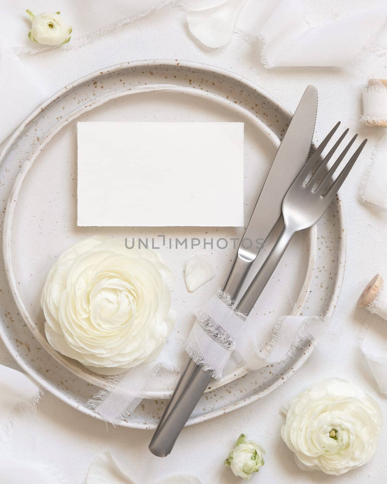 Wedding table setting with card near cream roses and white silk ribbons top view, mockup. Romantic scene with horizontal table place card and pastel flowers. Valentines, Spring or Mothers day concept