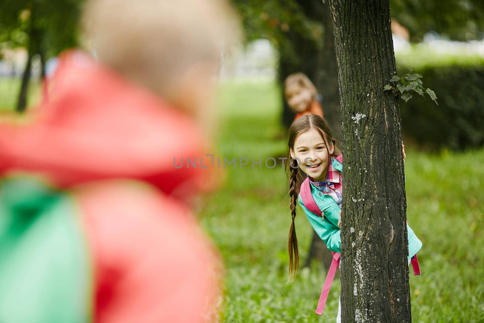 Little girl looking at camera out of tree trunk