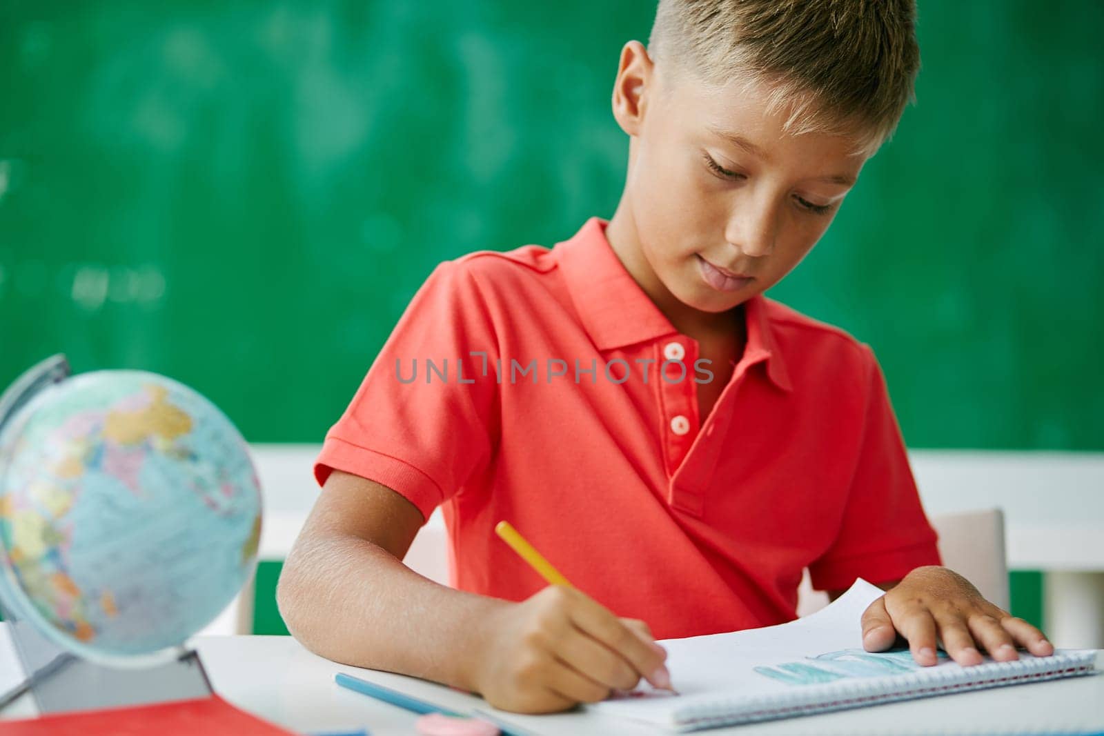 Clever schoolboy drawing at lesson in school