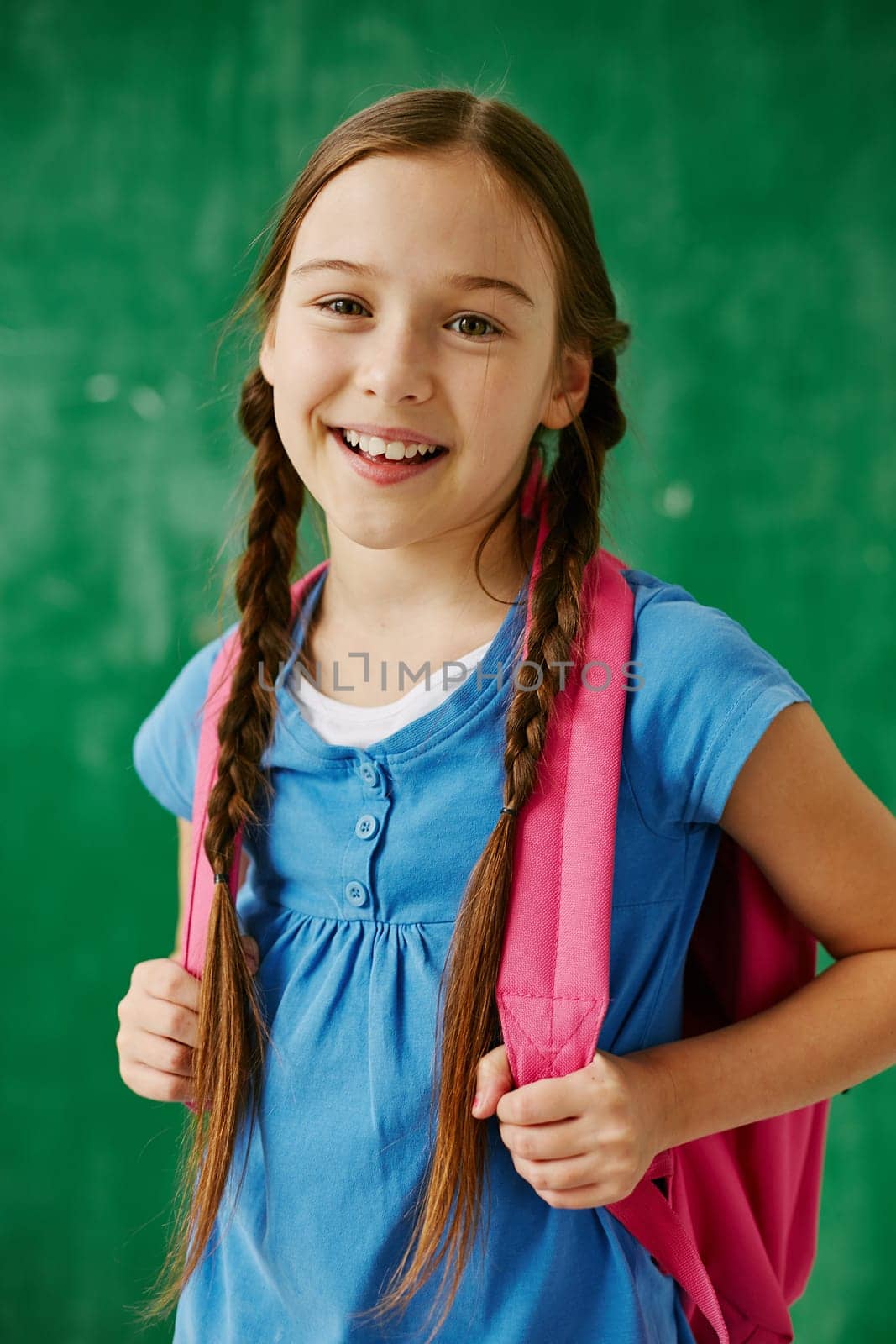Cheerful schoolgirl with backpack looking at camera