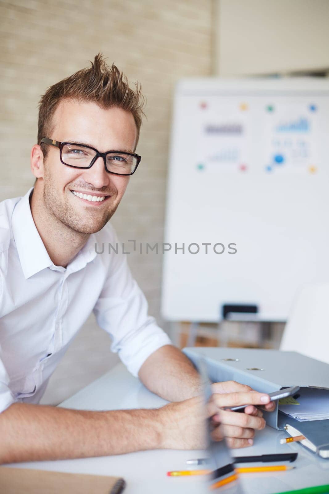 Smiling businessman in eyeglasses looking at camera in office