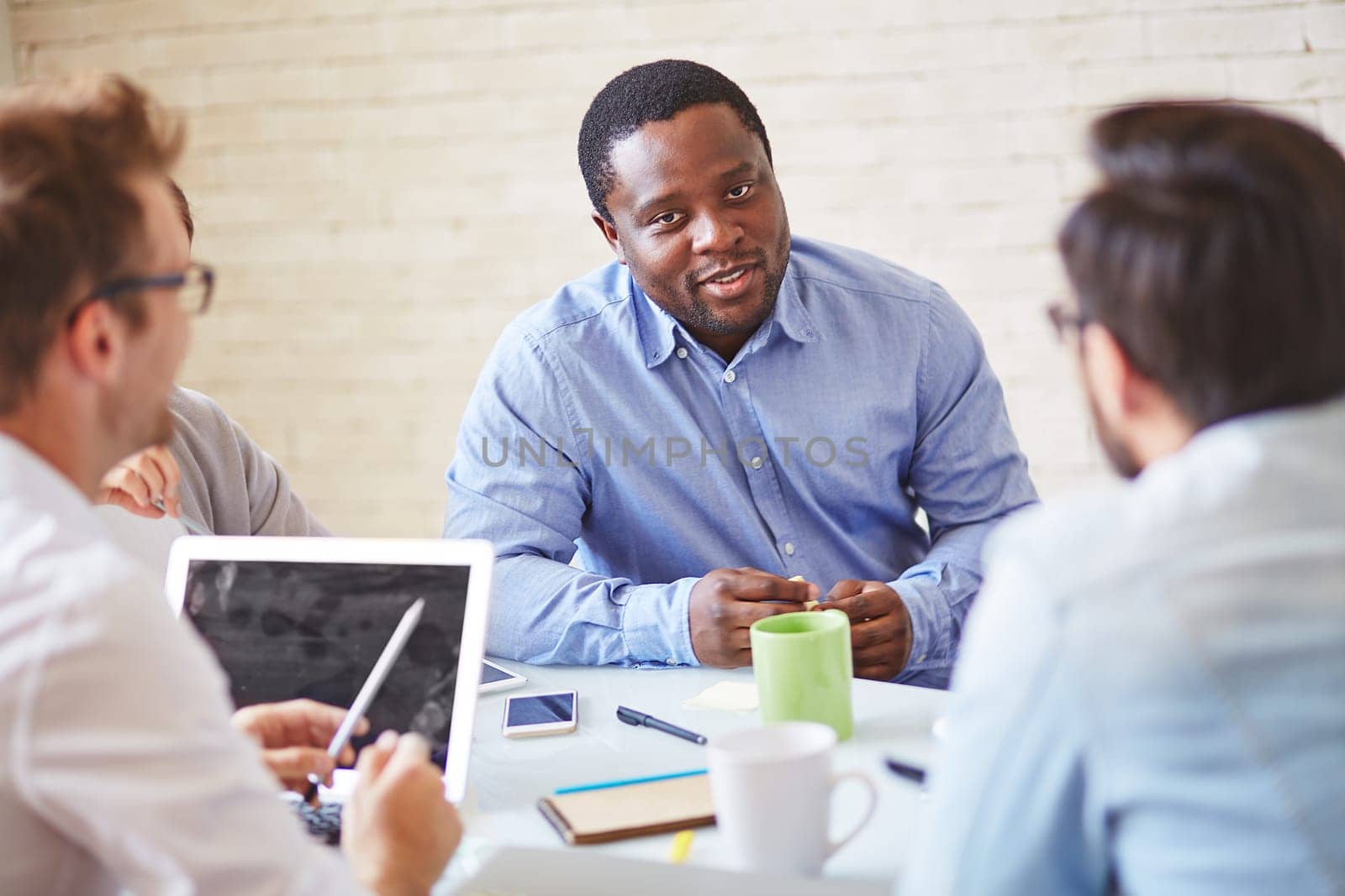 Serious manager of African ethnicity talking to colleagues