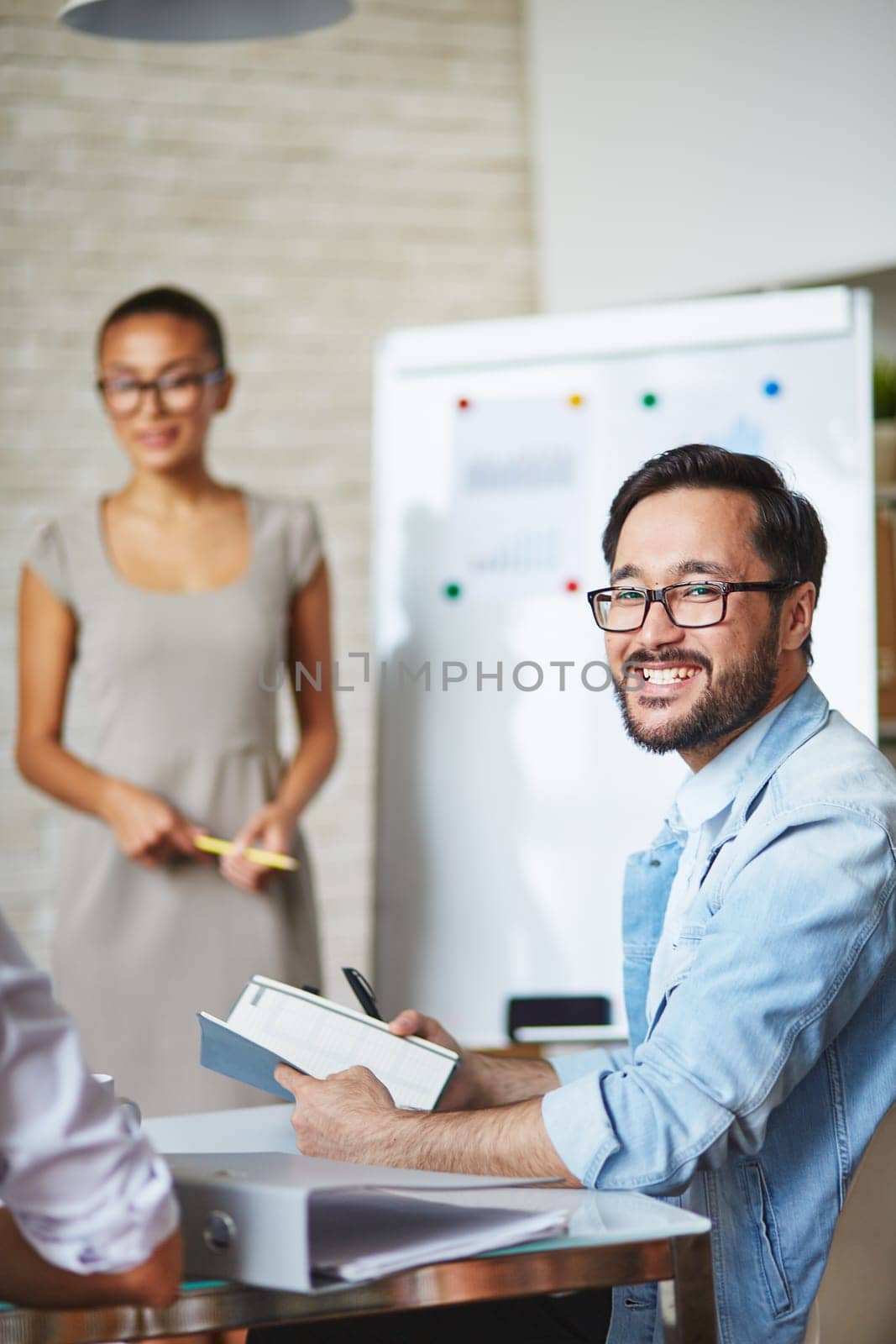Asian businessman in eyeglasses looking at camera with smile in working environment