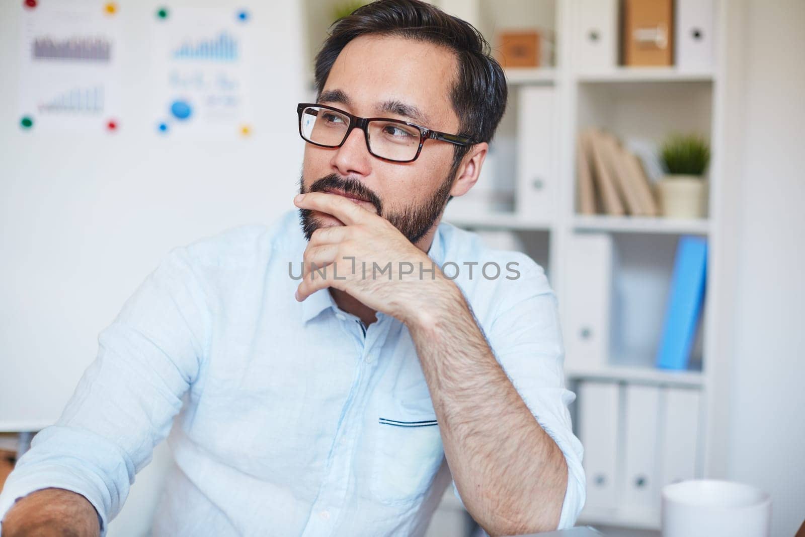 Pensive businessman in eyeglasses sitting in office