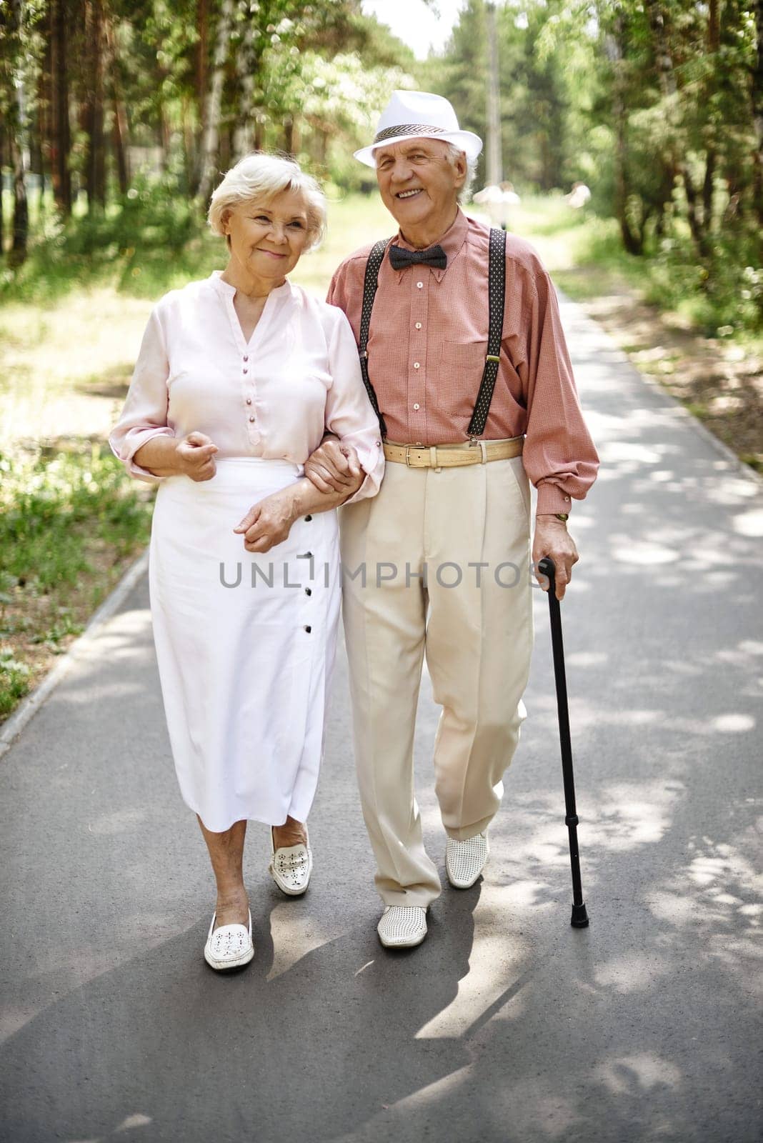 Affectionate seniors in smart casual going down park road