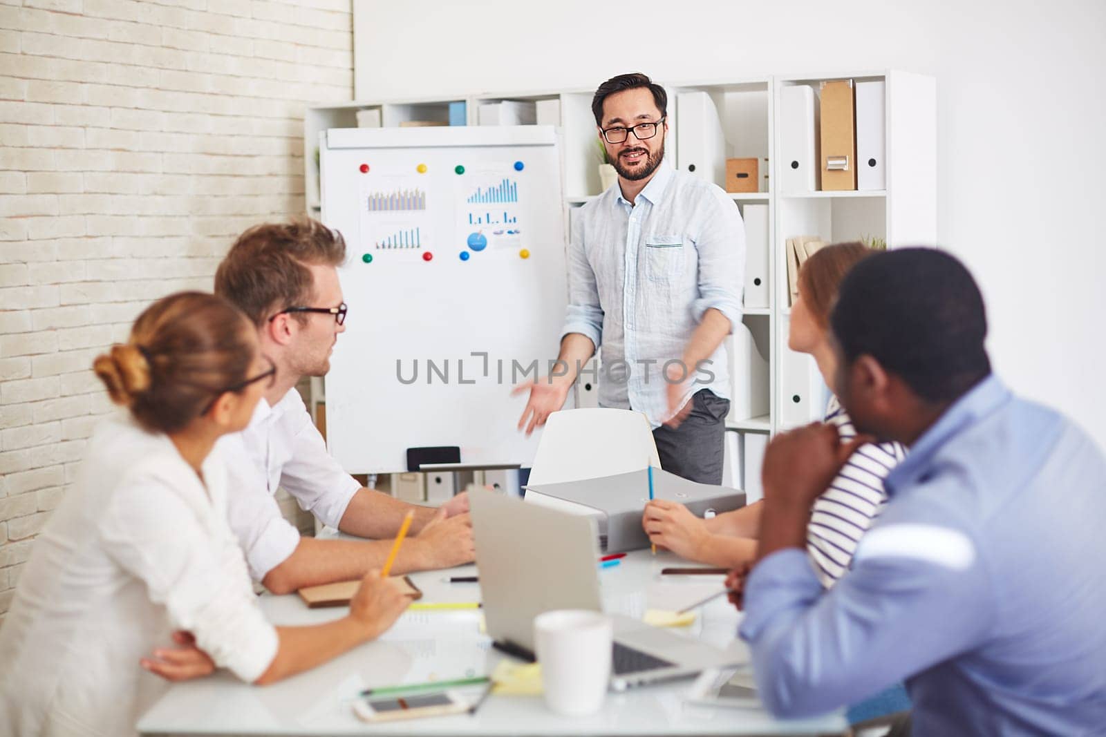 Modern employees listening to handsome teacher explaining subject at seminar