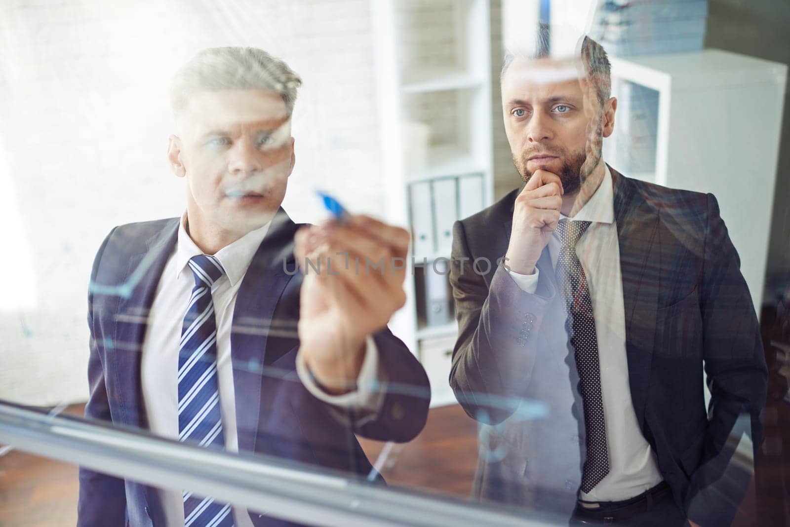 Male employee explaining graph on transparent board
