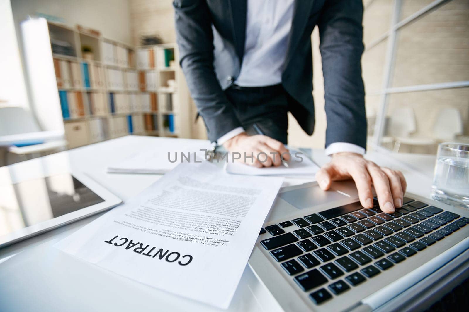 Businessman in formalwear pushing laptop buttons in office
