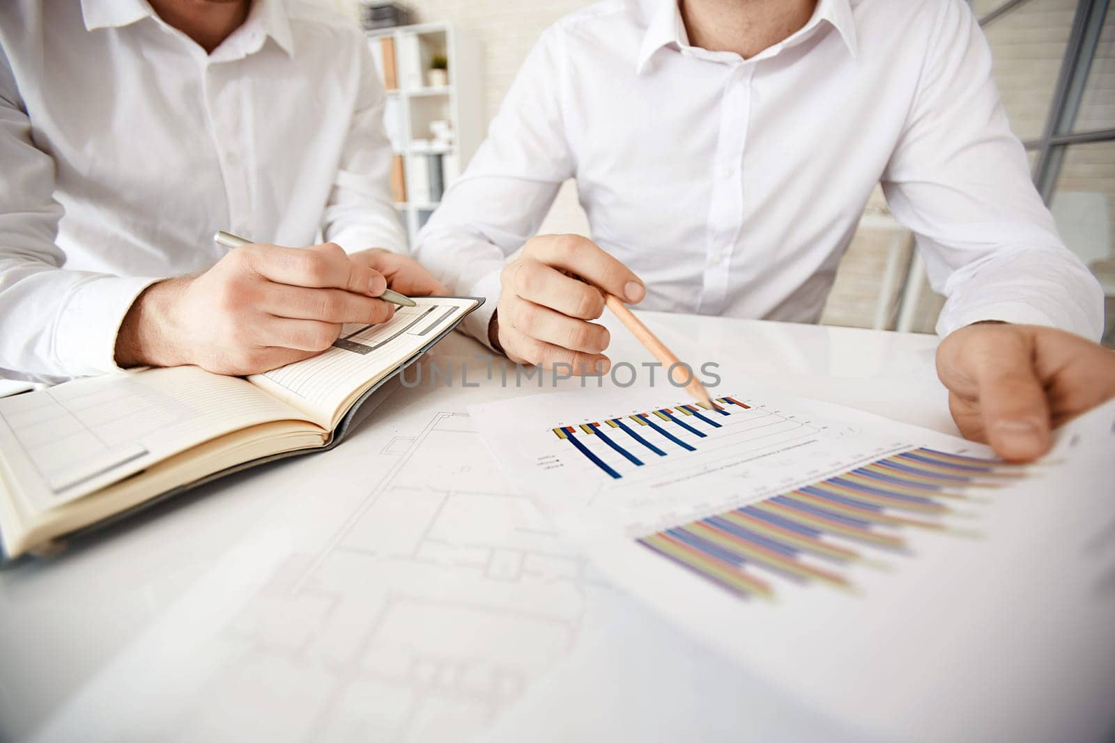Group of businessmen explaining chart and making notes