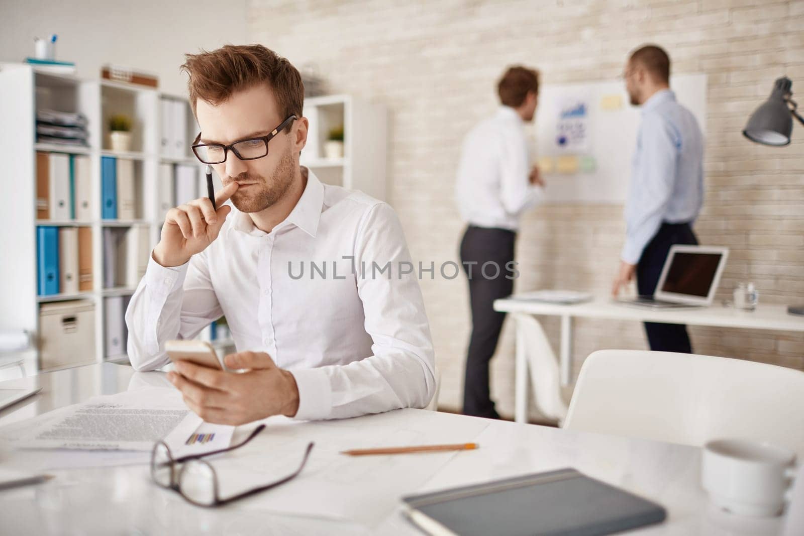 Serious businessman writing or reading sms in working environment