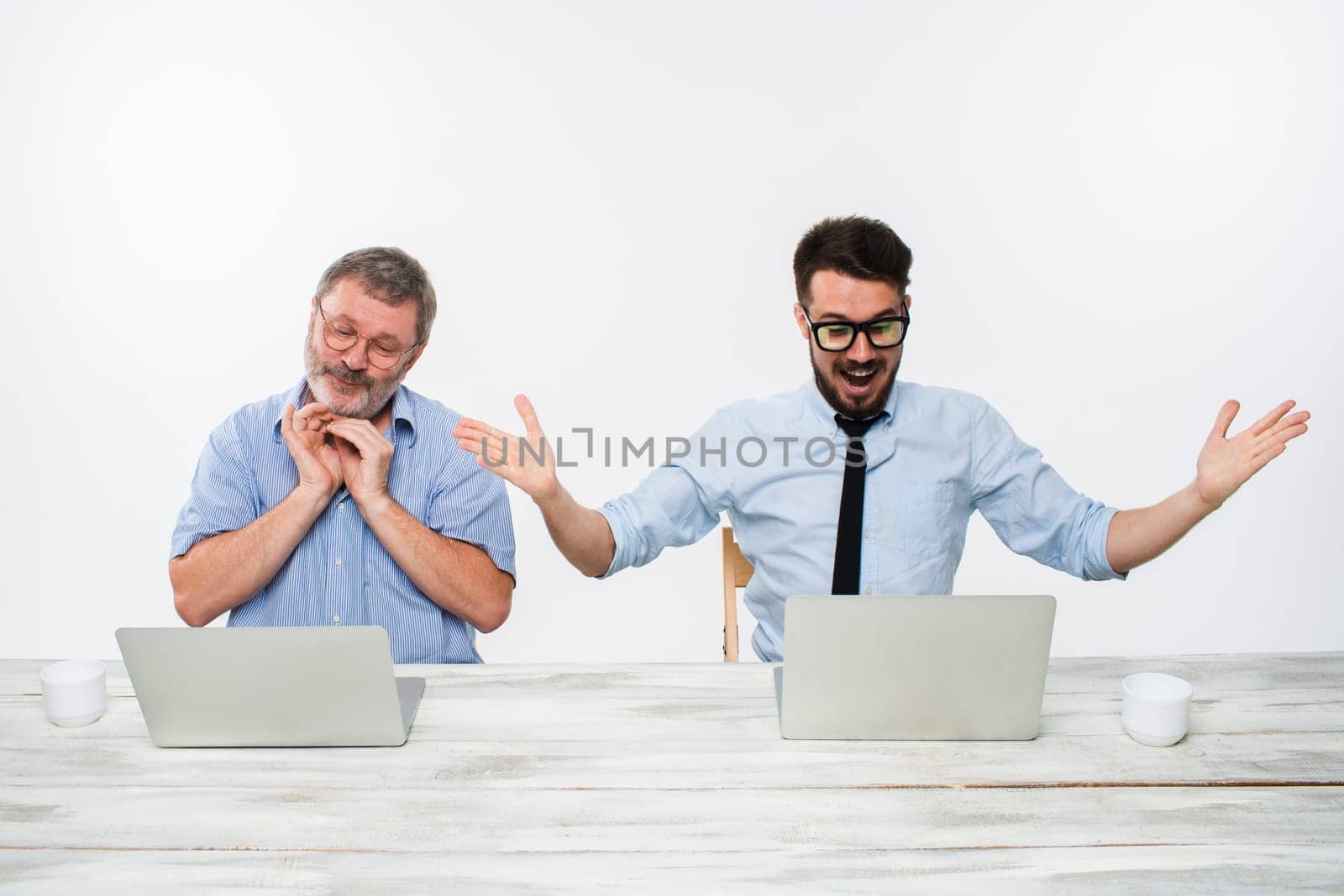 The two colleagues working together at office on white  background. both are looking at the computer screens. Both surprised. concept of positive emotions and good news