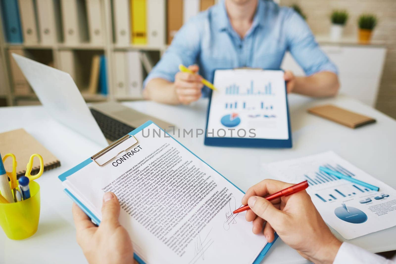 Male employee signing business agreement in working environment